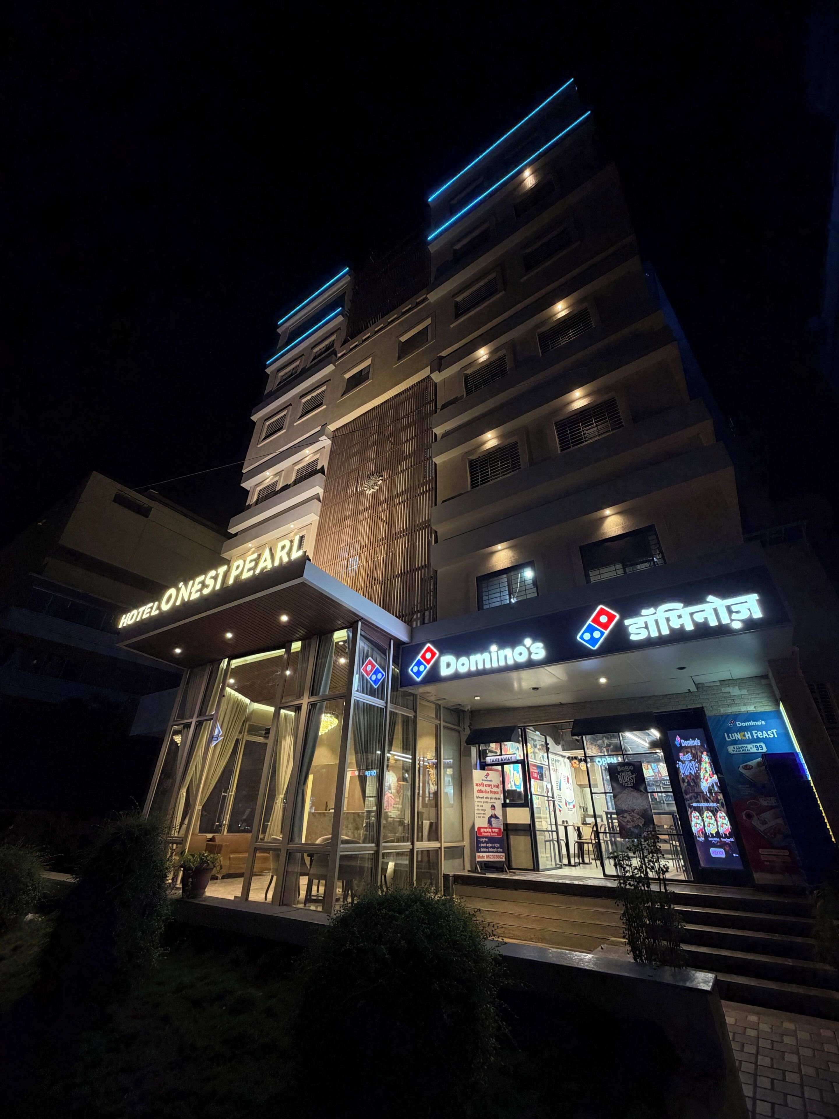 Un hotel con un cartello ben visibile per 'HOTEL O'NEST PEARL' e un locale Domino's Pizza.