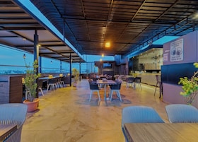 Un área de comedor al aire libre con mesas y sillas, una zona de bar y vistas a la ciudad.