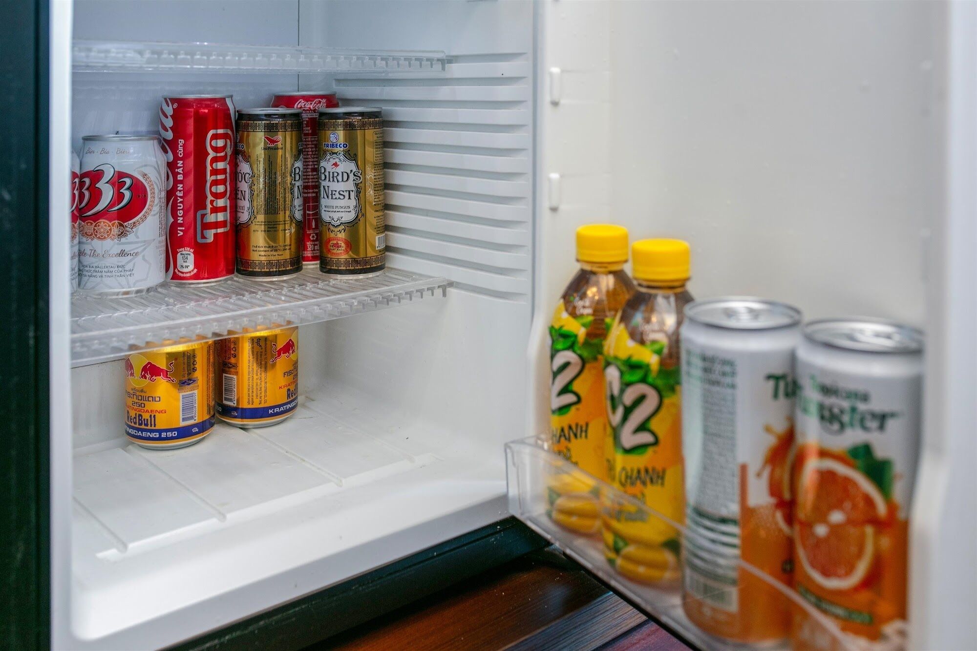 Un frigorifero con diverse bevande, tra cui lattine e bottiglie.