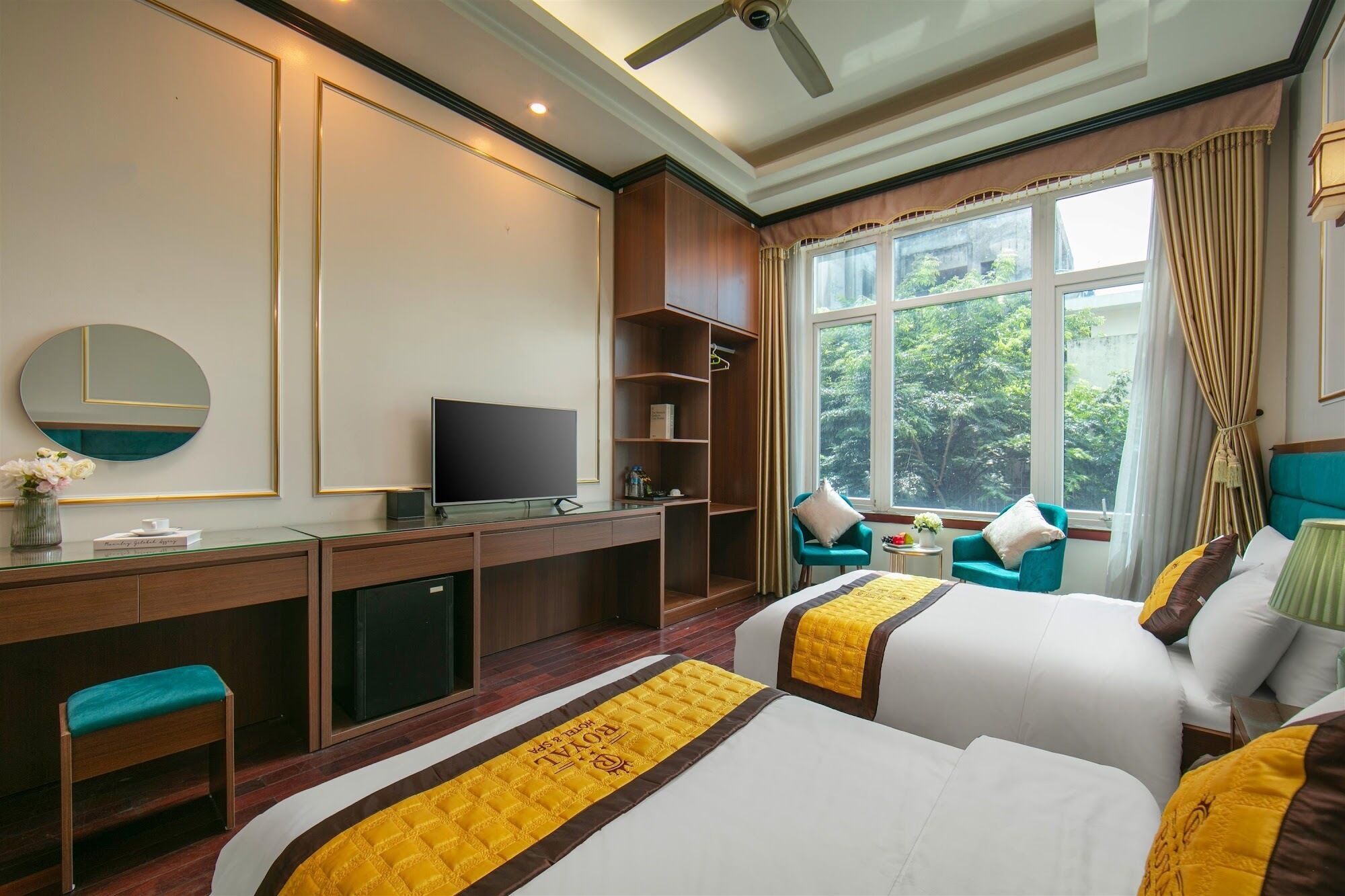 A hotel room with two beds, a desk with a TV, a chair, and a window with curtains.