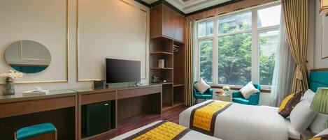 A hotel room with two beds, a desk with a TV, a chair, and a window with curtains.
