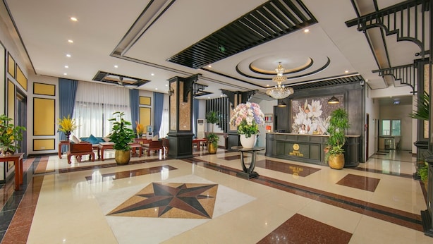 Un'ampia hall con un pavimento decorato con un motivo a stella, una reception e una scala.