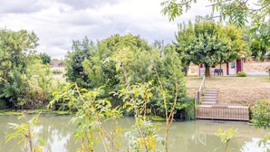Un estany amb una plataforma de fusta, envoltat de vegetació abundant i arbres.