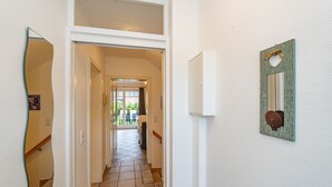A hallway with a tiled floor, a door leading to a balcony, and a wall-mounted light fixture. - Haus Conwind Apartment 1 - Comfortable vacation apartment Syltkoje with terrace and (Sylt-Ost)