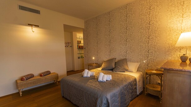 A neatly arranged bedroom with a large bed, a bedside table, a lamp, and a bench with towels. - SkyAttic - 801 by Houset (Milano)