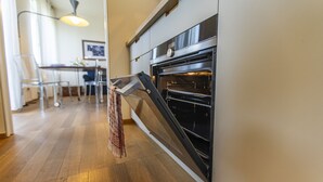 A modern kitchen with a built-in oven, wooden flooring, and a dining area with a table and chairs. - SkyAttic - 801 by Houset (Milano)