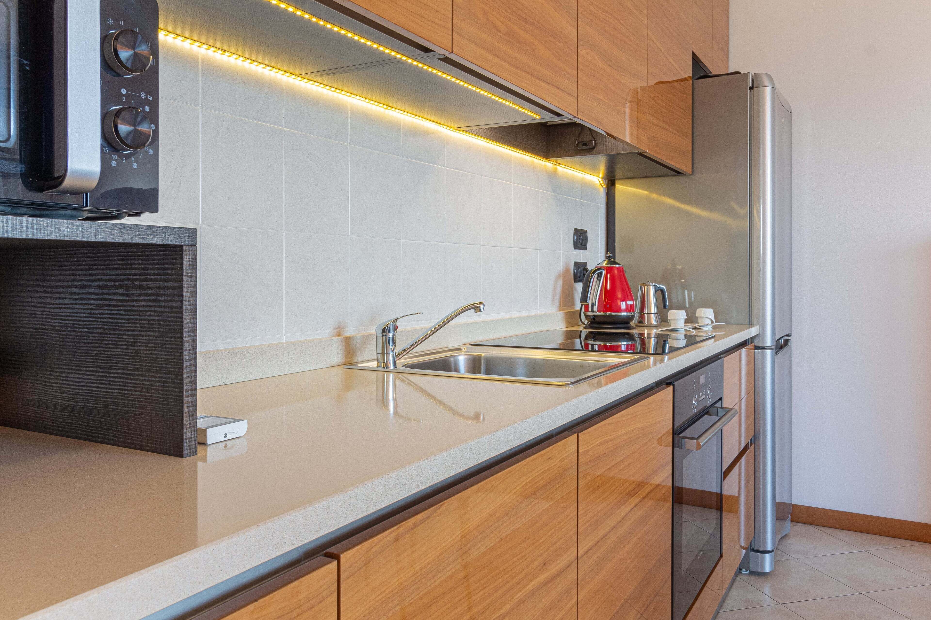 Eine moderne Küche mit Edelstahlkühlschrank, Einbauofen, Geschirrspüler und Kaffeemaschine.