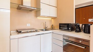 A modern kitchen with white cabinets, a stainless steel range hood, a microwave, and a coffee maker.