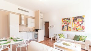 A modern living space with a dining area, kitchen, and a sofa set.