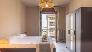 A bedroom with a bed, bedside table, wardrobe, and a view of the outside balcony. - Urban House - 301 by Houset (Monza)