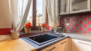 A modern kitchen with a black sink, white cabinets, and a window with sheer curtains. - Urban House - 301 by Houset (Monza)