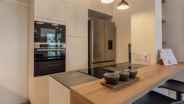 Una cocina moderna con electrodomésticos de acero inoxidable, una encimera de madera e iluminación colgante.