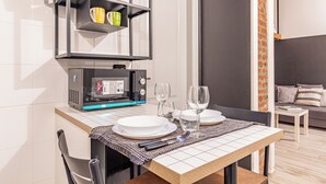 A modern kitchen with a built-in microwave, a coffee machine, and a shelf with mugs and a plant.