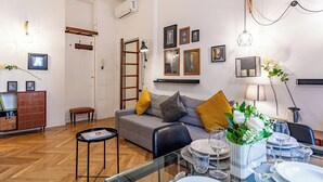 A modern living room with a sofa, dining table set, and various wall-mounted lights.
