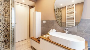 A modern bathroom with a freestanding bathtub, a large mirror, and patterned tiles. - Isolino Bridge Apartment by Houset (Monza)