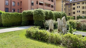 A residential area with a pathway, neatly trimmed hedges, and stone sculptures. - Cielo C18 by Houset - Two Bedroom Apartment, Sleeps 5 (Cinisello Balsamo)
