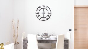 A dining area with a marble table, white chairs, and a wall clock. - Cascina Fedeli by Houset (Monza)