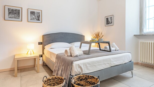 A modern bedroom with a bed, bedside tables, and two framed pictures on the wall. - Cascina Fedeli by Houset (Monza)