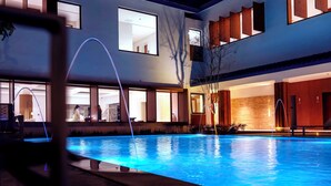 Un hotel moderno con una amplia piscina cubierta, múltiples ventanas y un interior bien iluminado.