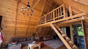 A wooden cabin interior with a loft bedroom, a sofa, a coffee table, and a staircase. - Villa Cottage Merisi (Keda)