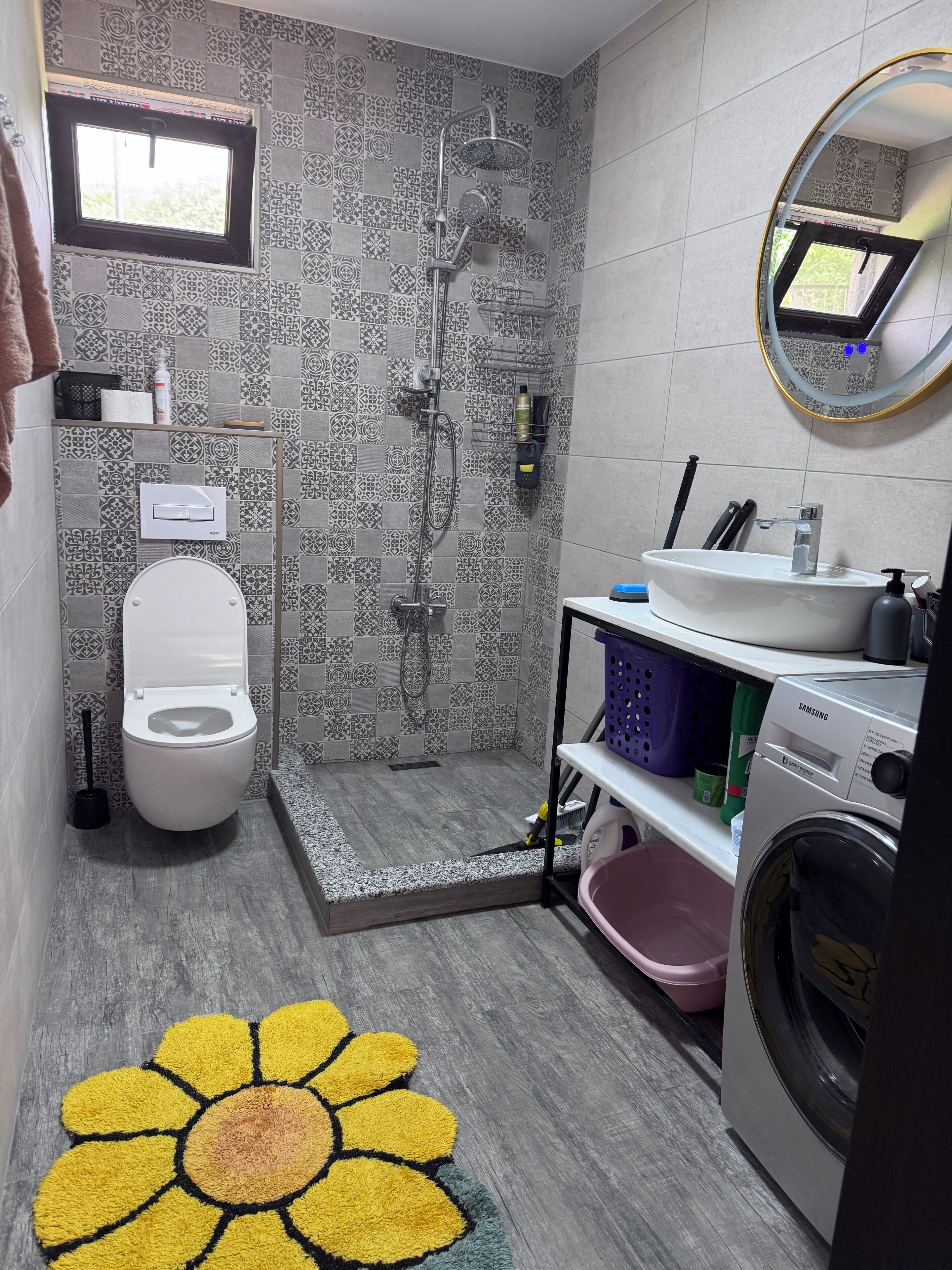 Un bagno dotato di doccia, toilette, lavandino e lavatrice.