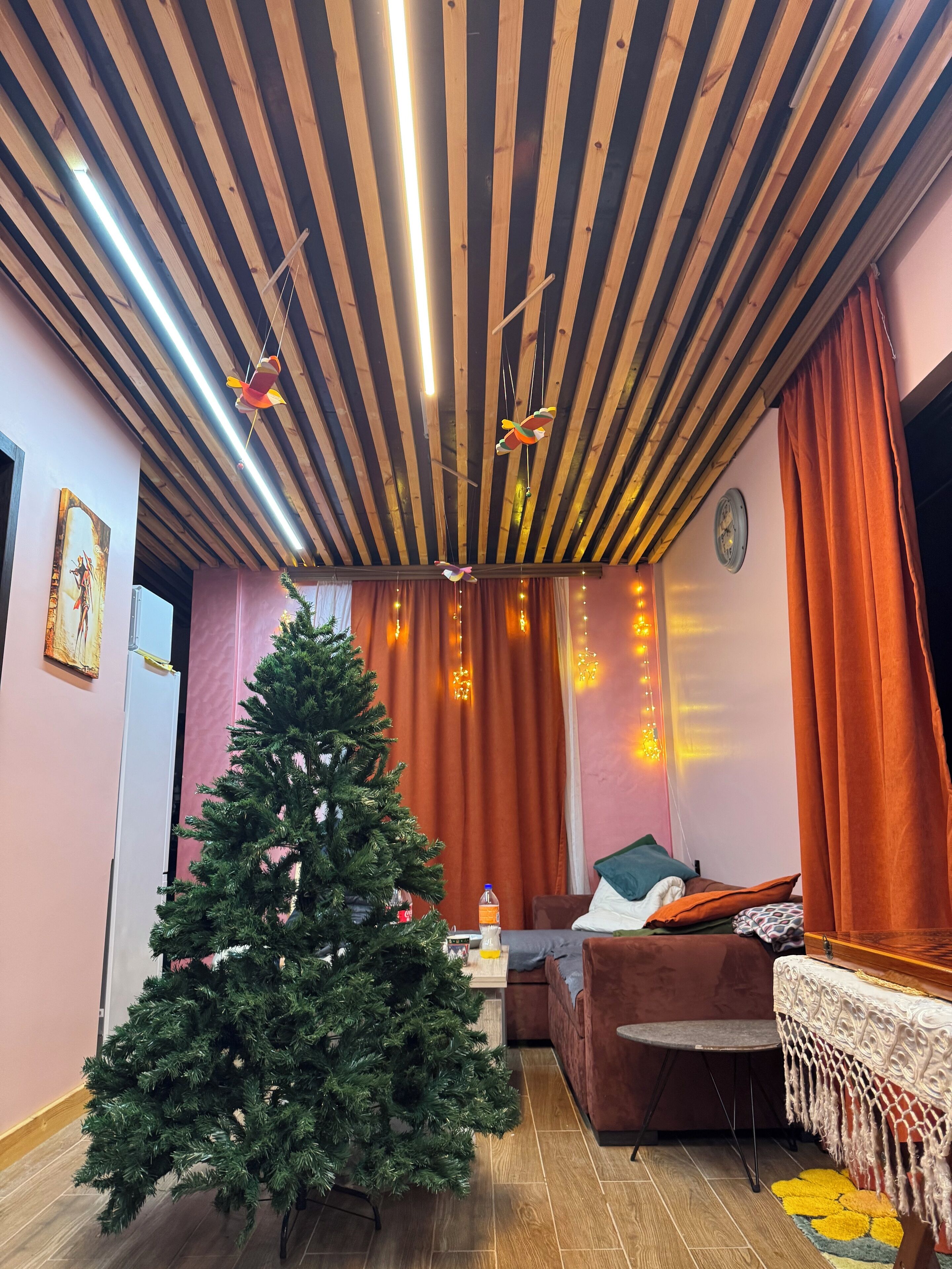 Un accogliente soggiorno con soffitto in legno, un albero di Natale, un divano e un tavolo con copritavolo decorativo.
