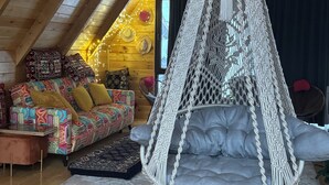 A cozy loft with a macrame hanging chair, a colorful sofa, and a wooden ceiling. - Villa Cottage Merisi (Keda)