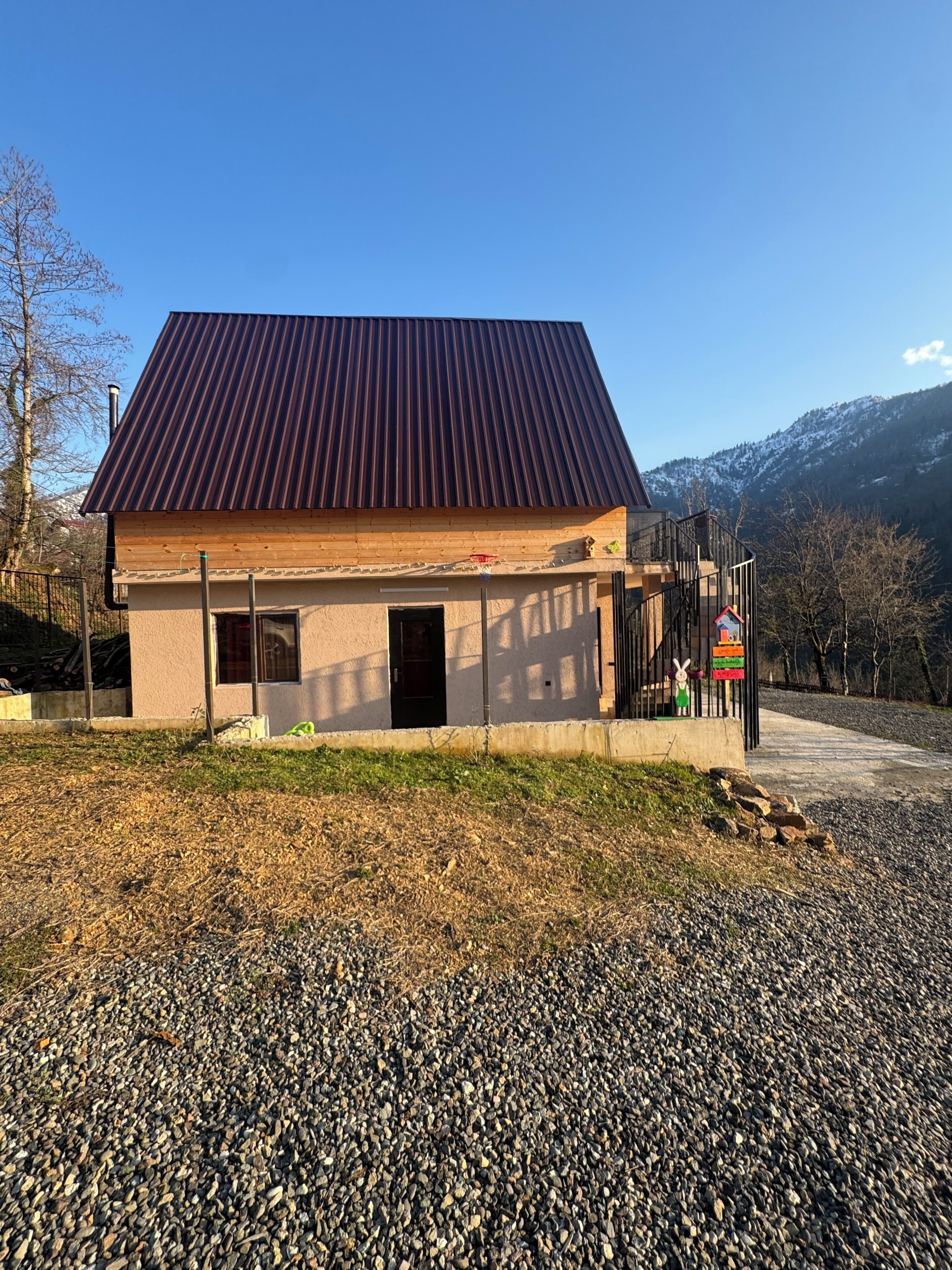 A building with a metal roof, wooden walls, and a gravel driveway.