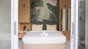 Une chambre moderne avec un grand lit, des meubles en bois et une fresque murale représentant des feuilles tropicales.