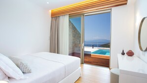 Ein modernes Schlafzimmer mit einem großen Bett, einer Holzbalkendecke, einer Glastür, die auf einen Balkon mit einem Pool führt, und einer weißen Kommode.