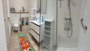 A modern bathroom with a glass shower enclosure, a white sink with a soap dispenser, and a colorful rug. - Vacation home near Porto Vecchio (Porto-Vecchio)