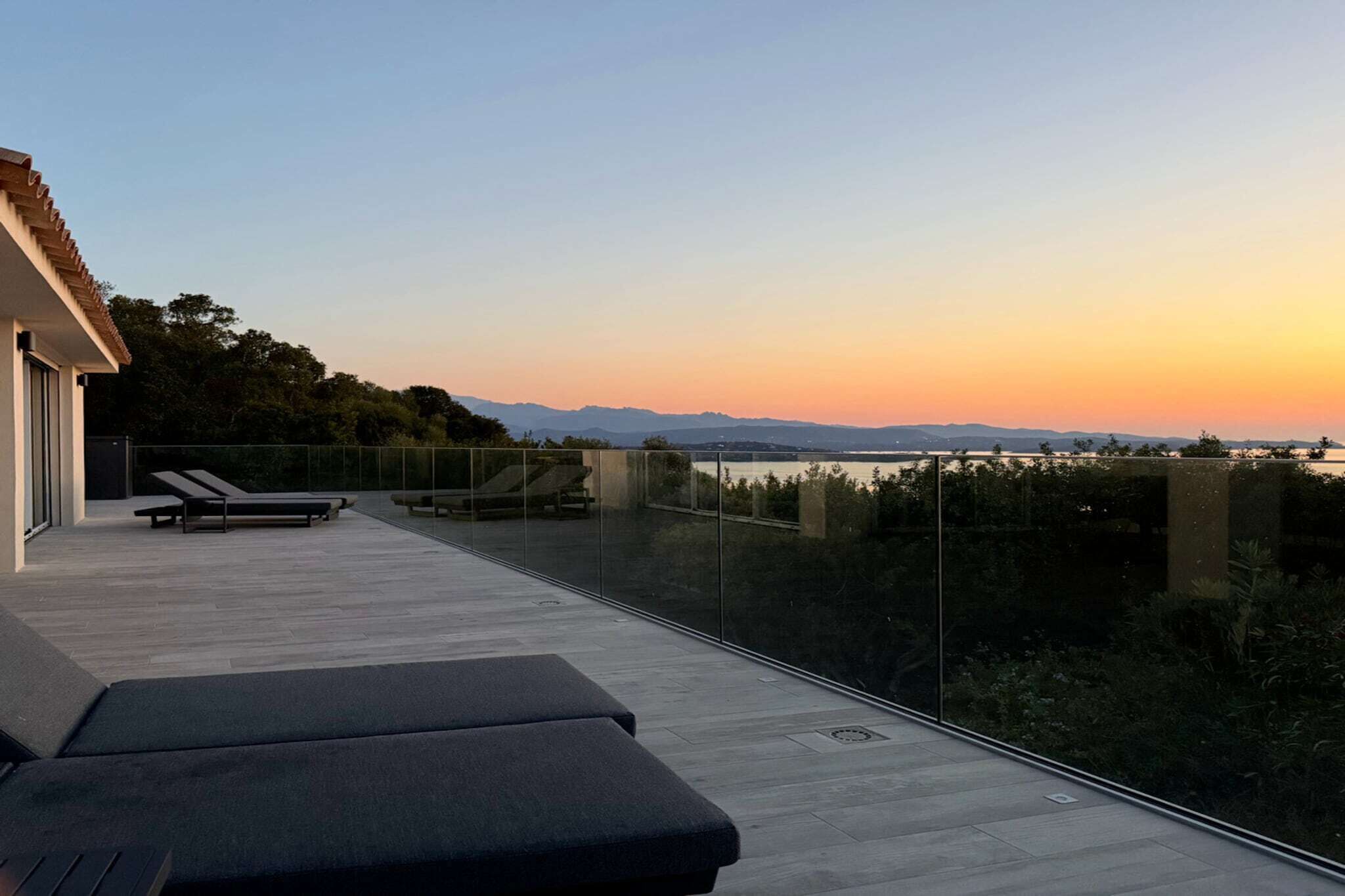 A modern outdoor terrace with a view of the sunset and mountains.