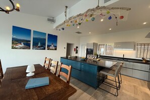A modern kitchen with a central island, blue cabinets, and a dining area with a wooden table and chairs.