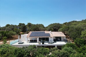 Une maison moderne avec un toit plat, des panneaux solaires et une piscine.