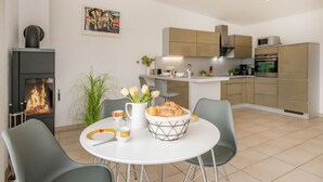 Una cocina moderna con una isla central, un comedor con sillas y una chimenea.