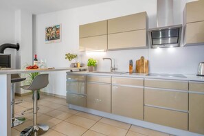 Uma cozinha moderna com ilha central, eletrodomésticos de aço inoxidável e um banquinho de bar.