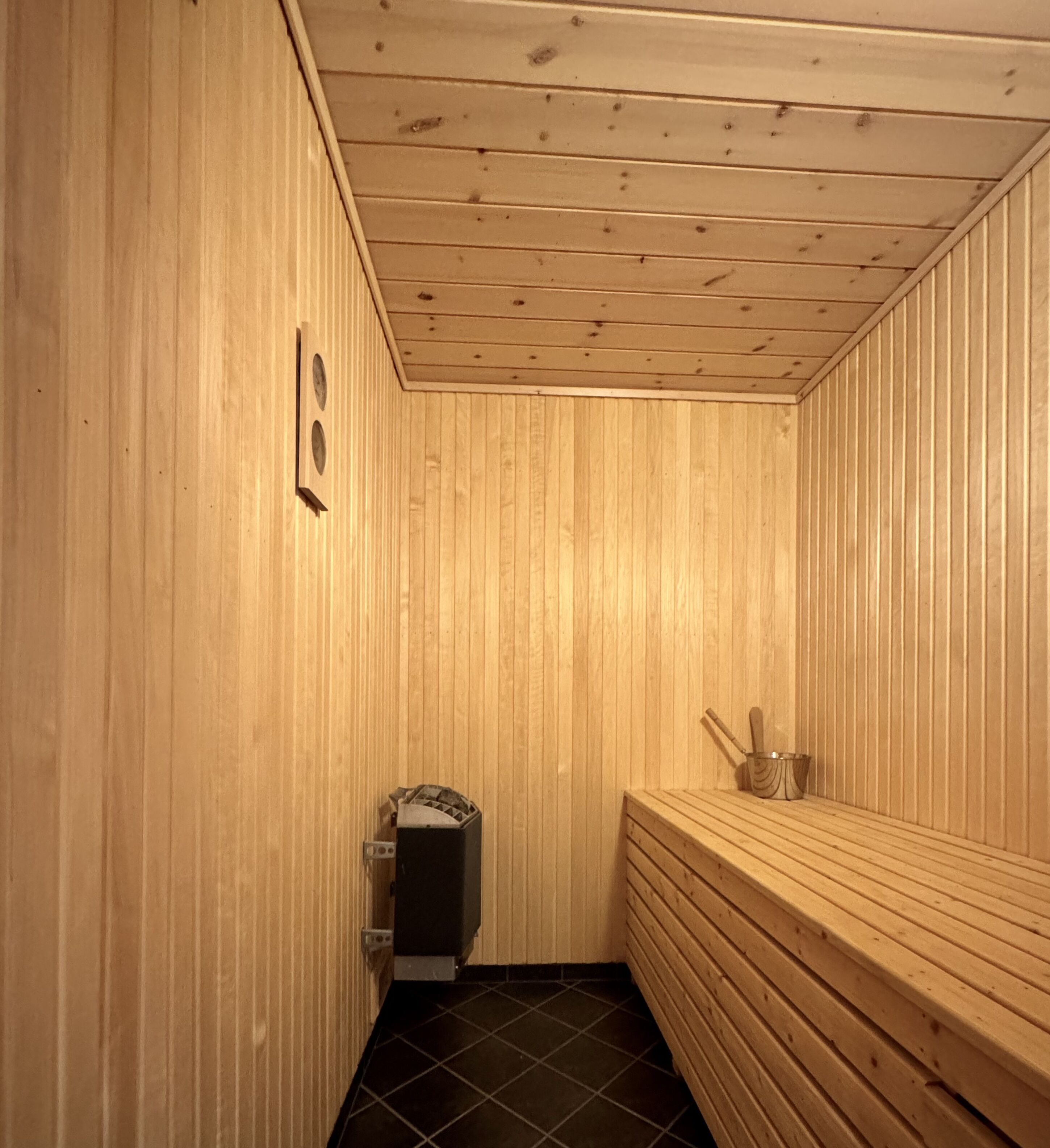 A sauna room with wooden walls and a bench.