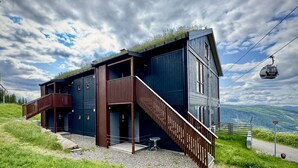 A modern building with a wooden exterior, a staircase, and a view of the surrounding landscape.