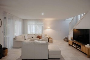 Ein modernes Wohnzimmer mit einer Eckcouch, einem Fernseher und einer Treppe.