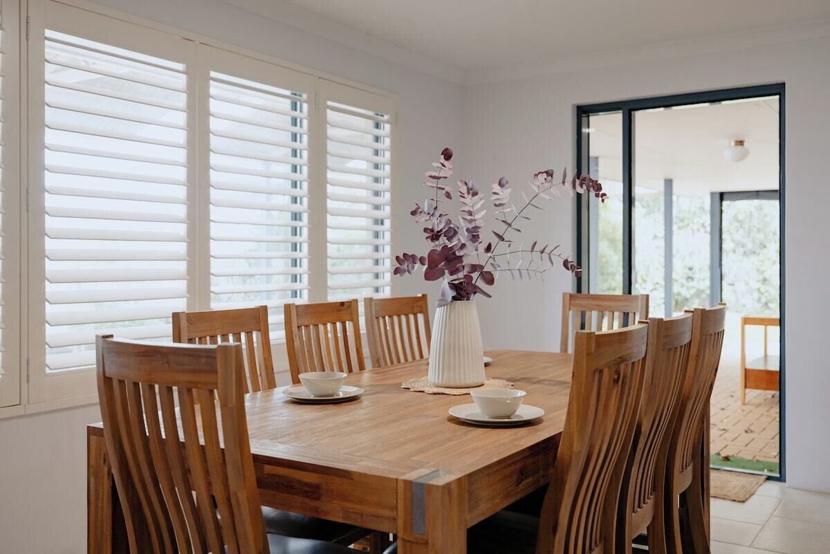 Un coin repas avec une table en bois, six chaises et un vase rempli de fleurs.