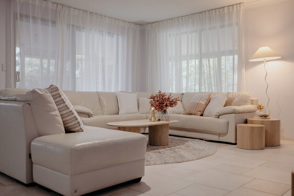 A modern living room with a sofa, ottoman, coffee table, and lamps.