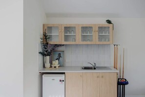 Eine kleine Küche mit Holzausstattung, einer eingebauten Spüle und einem kleinen Kühlschrank.