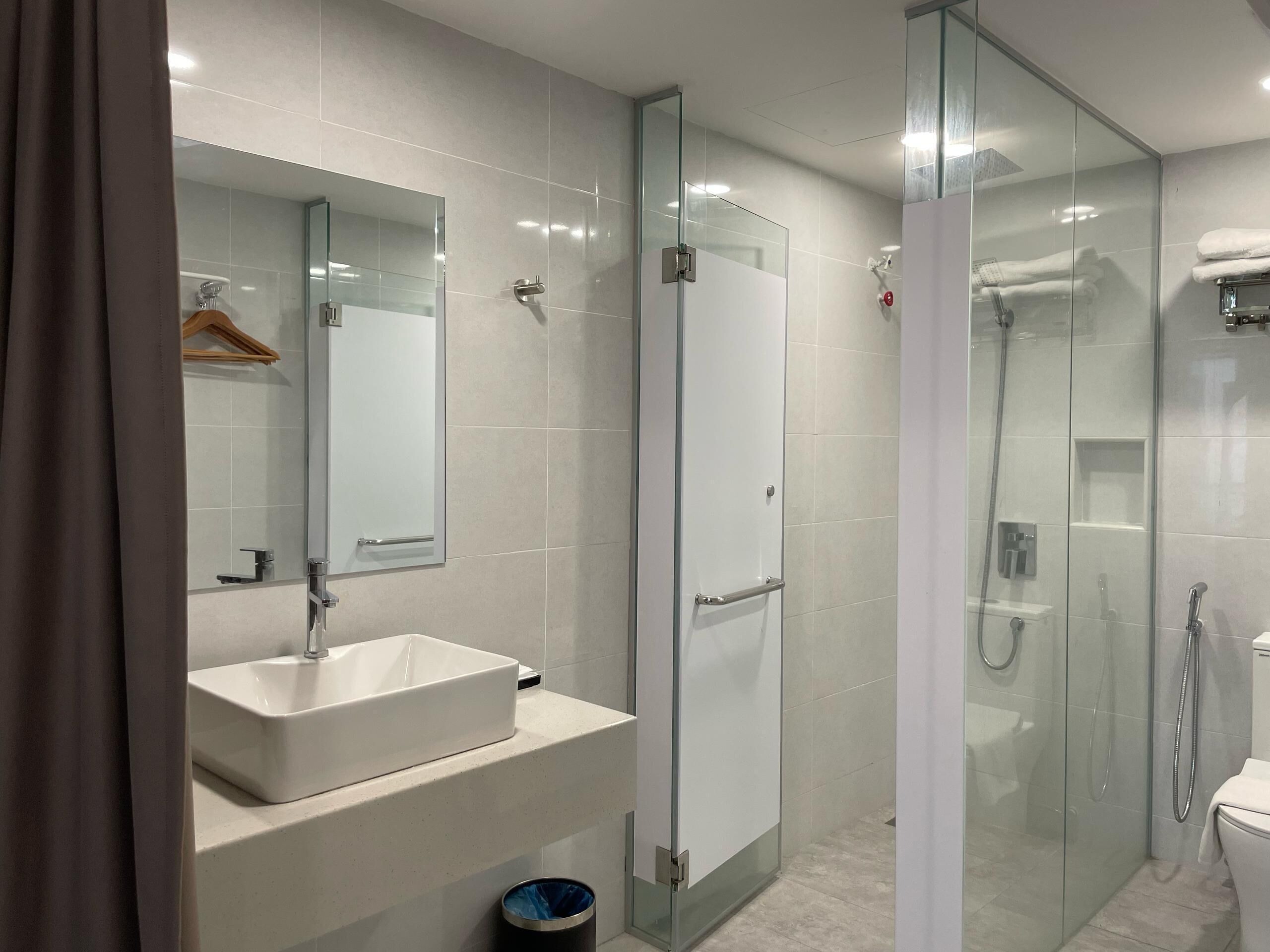 A modern bathroom with a glass-enclosed shower, a white sink, and a mirror above it.