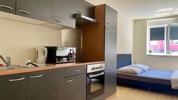 Una kitchenette compacta con microondas, hervidor y horno.
