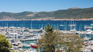 A marina with numerous boats docked, surrounded by a coastal town and hills in the background. - Akademis Fit Split (Split)