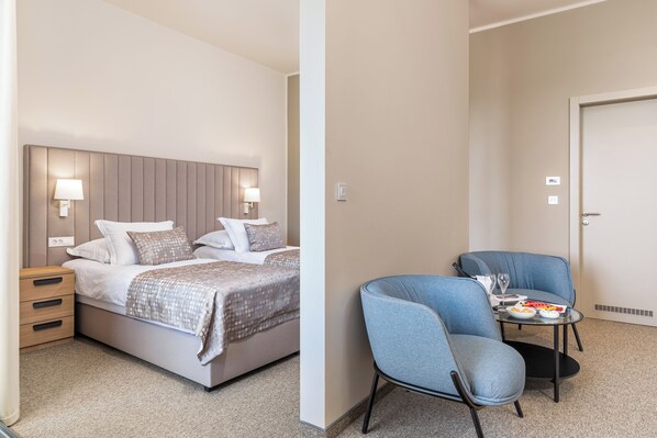 Habitación de hotel con cama, mesitas de noche, una silla y una pequeña mesa con un plato de comida y un vaso.
