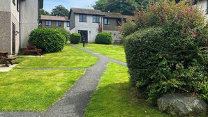 Un jardin bien entretenu, avec un chemin de gravier menant à une maison dont le toit est recouvert de tuiles.