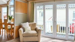 A cozy living room with a sofa, a dining table with chairs, and a sliding glass door leading to a balcony. - 2 bedroom accommodation in Patrington Haven (Patrington Haven)