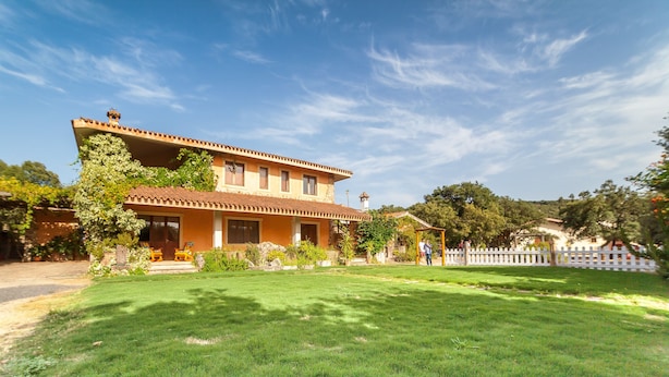 A two-story house with a tiled roof, a front porch, and a well-maintained lawn. - Farmhouse nestled in a cork oak forest with boungalows.  Pets allowed (Ulà Tirso)