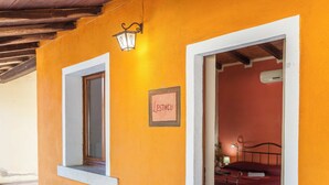 A room with a bed, a nightstand, and a wall-mounted lamp. - Farmhouse nestled in a cork oak forest with boungalows.  Pets allowed (Ulà Tirso)